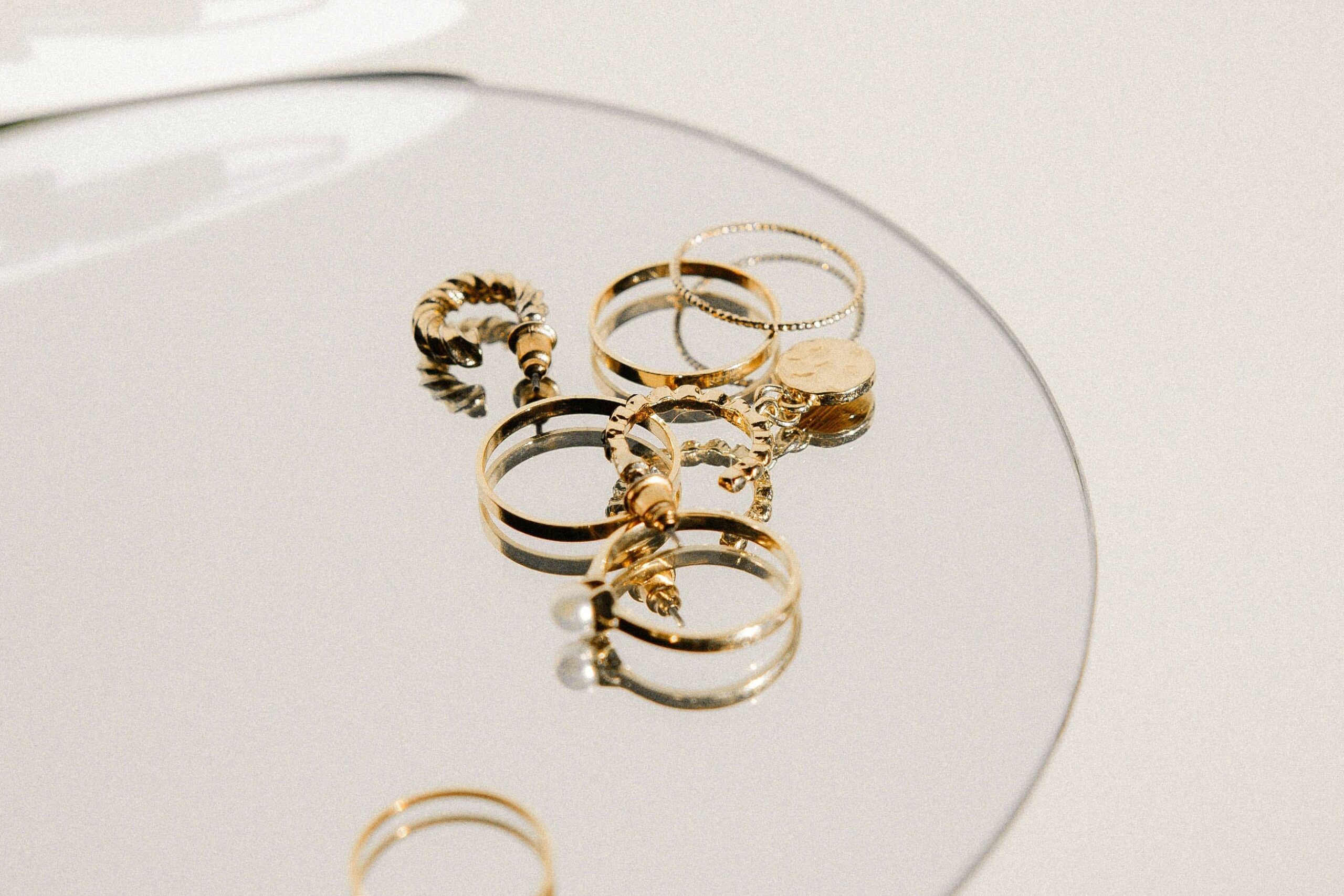 Insieme di anelli di oro usato bianco e giallo su un piattino di vetro pronti per la valutazione gratuita del compro oro terni