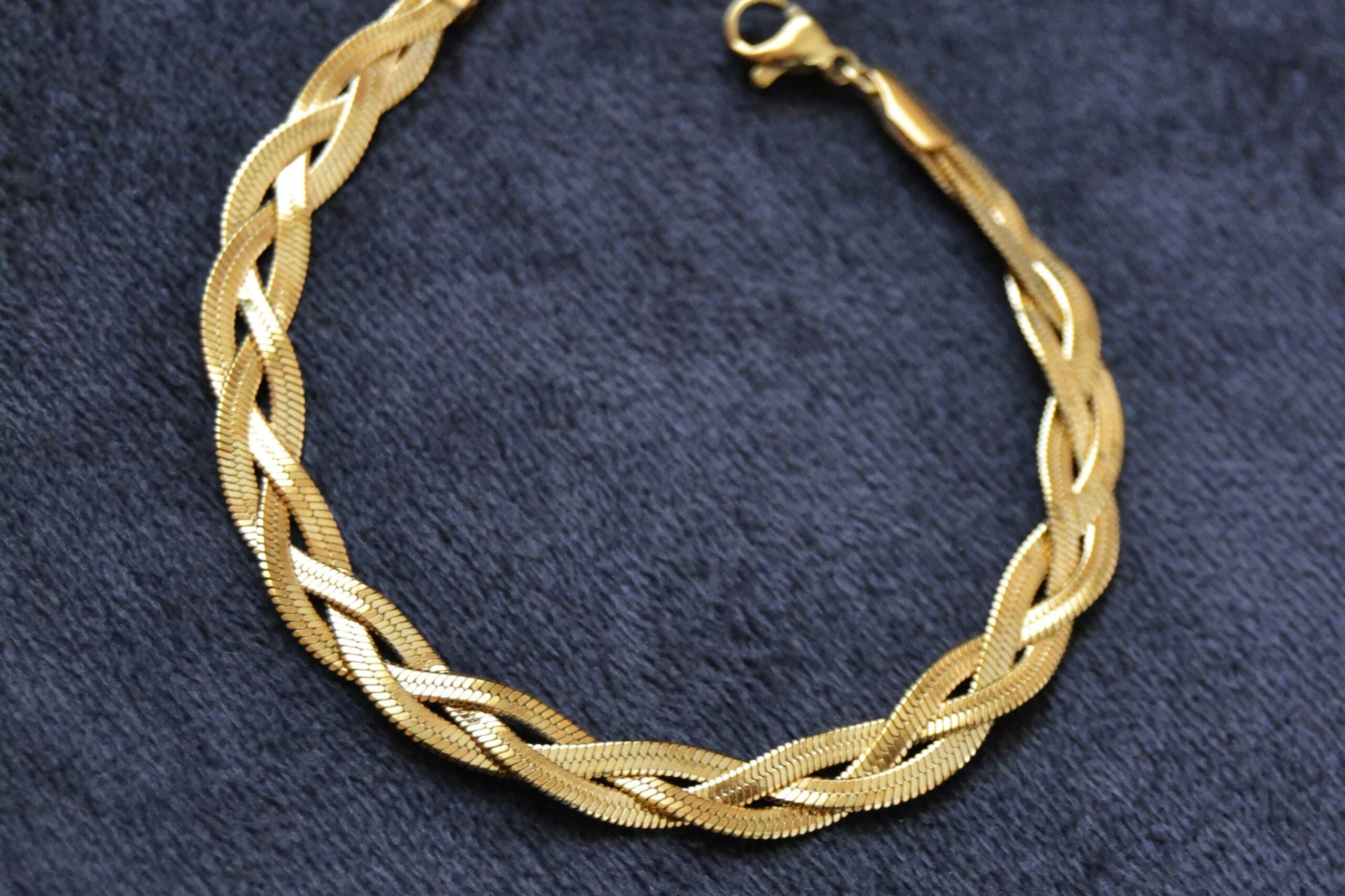 Collana d'oro giallo usato con trama intrecciata da poter vendere come oro usato. La collana d'oro si trova su un tappetino azzurro